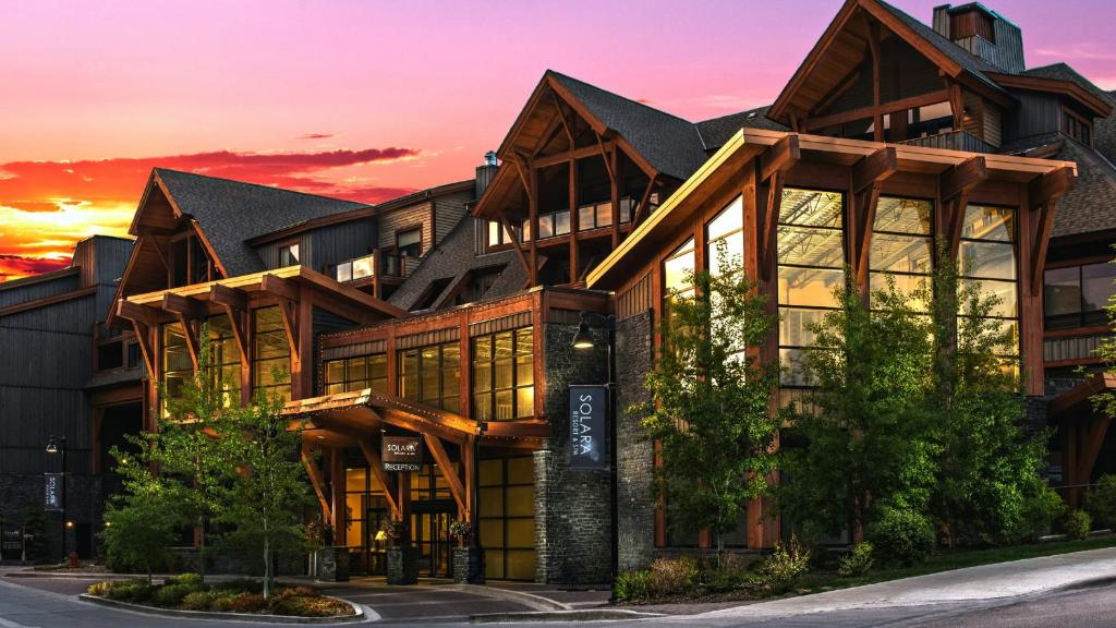 a large building with a sunset in the background at Solara Resort by Bellstar Hotels in Canmore
