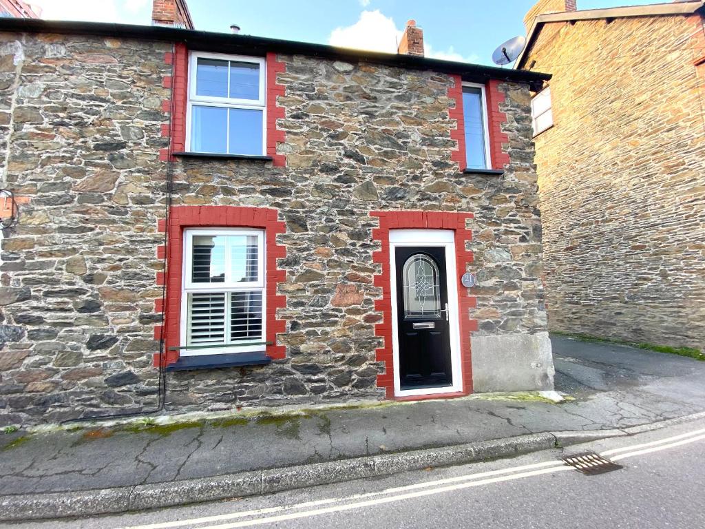 uma casa de pedra com janelas vermelhas e uma porta em 21 Cross Street em Lynton