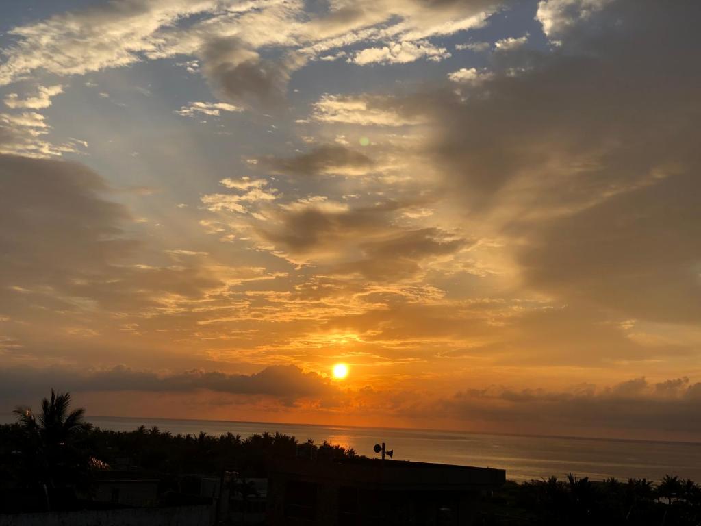 einen Sonnenuntergang über dem Meer mit der Sonne am Himmel in der Unterkunft 月光祝福民宿Moonlight Blessing Hostel in Chenggong