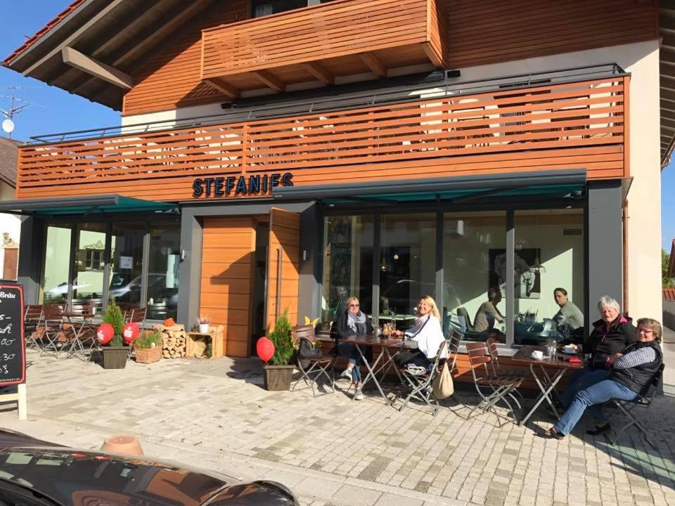 a group of people sitting at tables outside of a restaurant at Stefanies-Café-Pension-Kultur in Bad Feilnbach