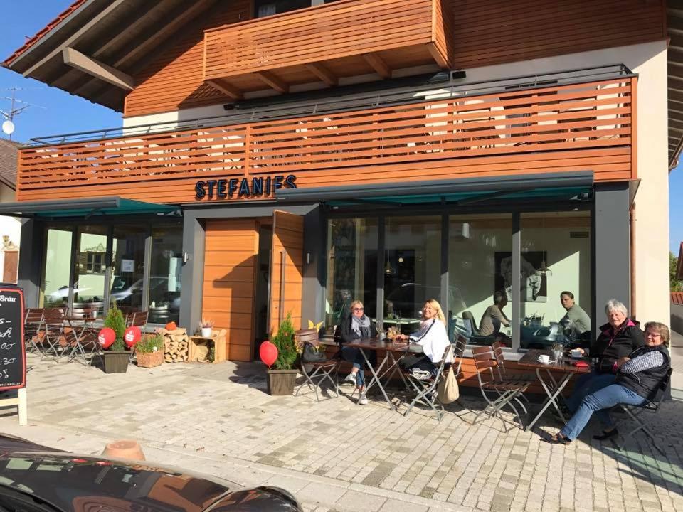 un grupo de personas sentadas en mesas fuera de un restaurante en Stefanies-Café-Pension-Kultur, en Bad Feilnbach