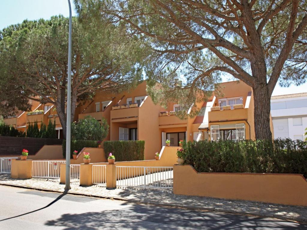 un edificio con una valla y árboles delante de él en Casa adosada en Playa de Pals by Apartaments Golf en Pals