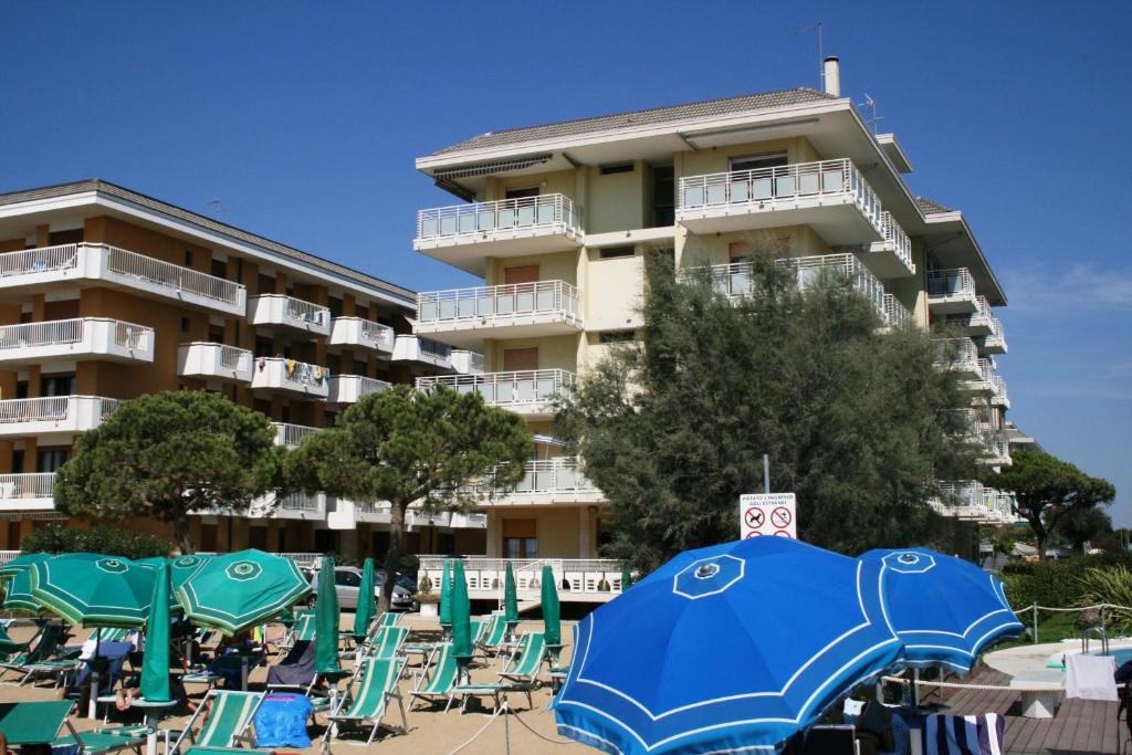 a group of chairs and umbrellas in front of a building at Diplomatic Apartment in Lido di Jesolo