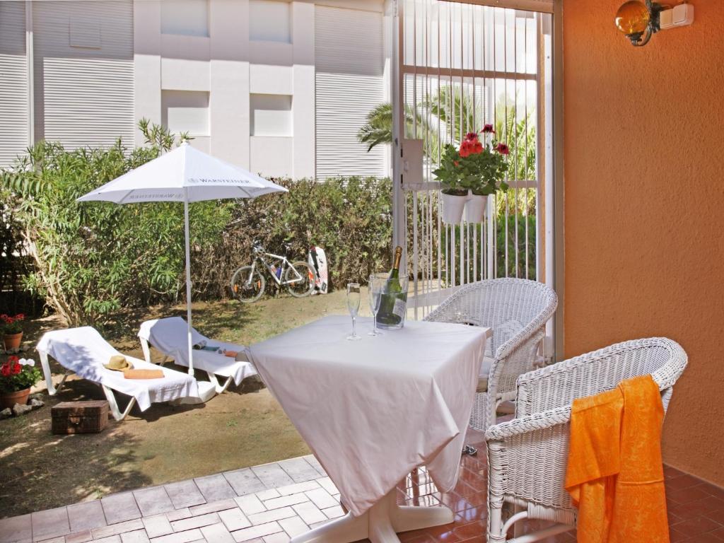 una mesa y sillas con una sombrilla en el patio en Casa adosada en Platja de Pals by Apartaments Golf, en Pals