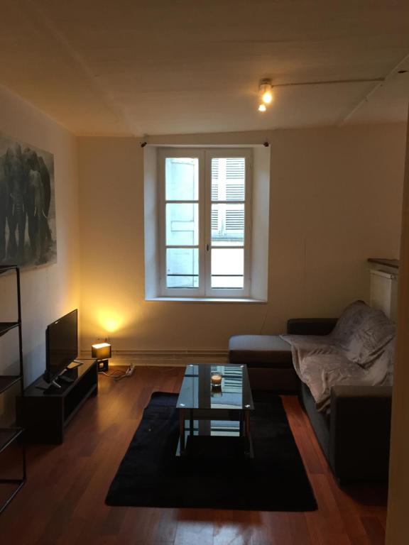 a living room with a couch and a window at Victor Hugo 2G et sa pizza offerte in Aurillac