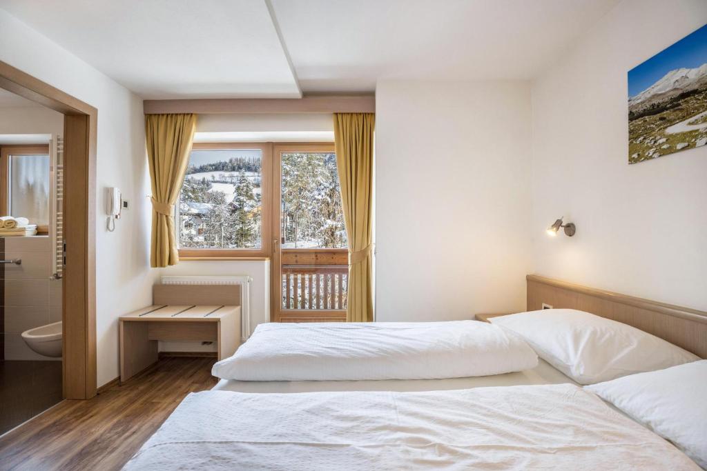 a bedroom with two beds and a window at Runcac Apt Salt in San Vigilio Di Marebbe