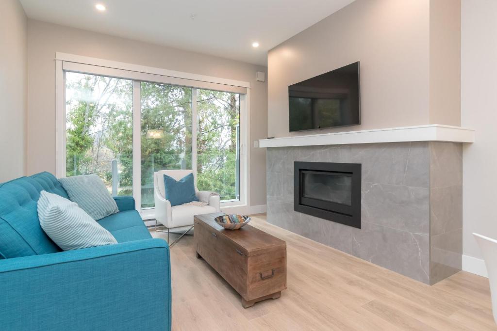 a living room with a blue couch and a fireplace at Coffee With A View, Brand New One Bedroom At Sooke Harbour in Sooke