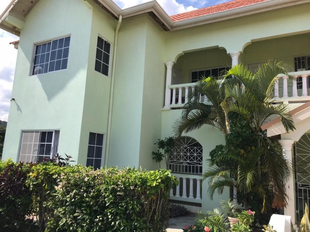 a white house with a palm tree in front of it at Beautiful 2-Bed Apartment in sunny Jamaica in Silver Sands