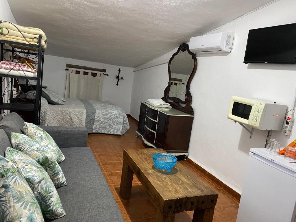 Habitación pequeña con cama, sofá y TV. en La Buhardilla de Torrecillas, en El Bosque