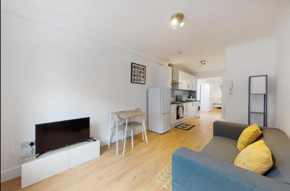 uma sala de estar com um sofá azul e uma cozinha em New Spacious 1 bed studio flat in Aldgate em Londres