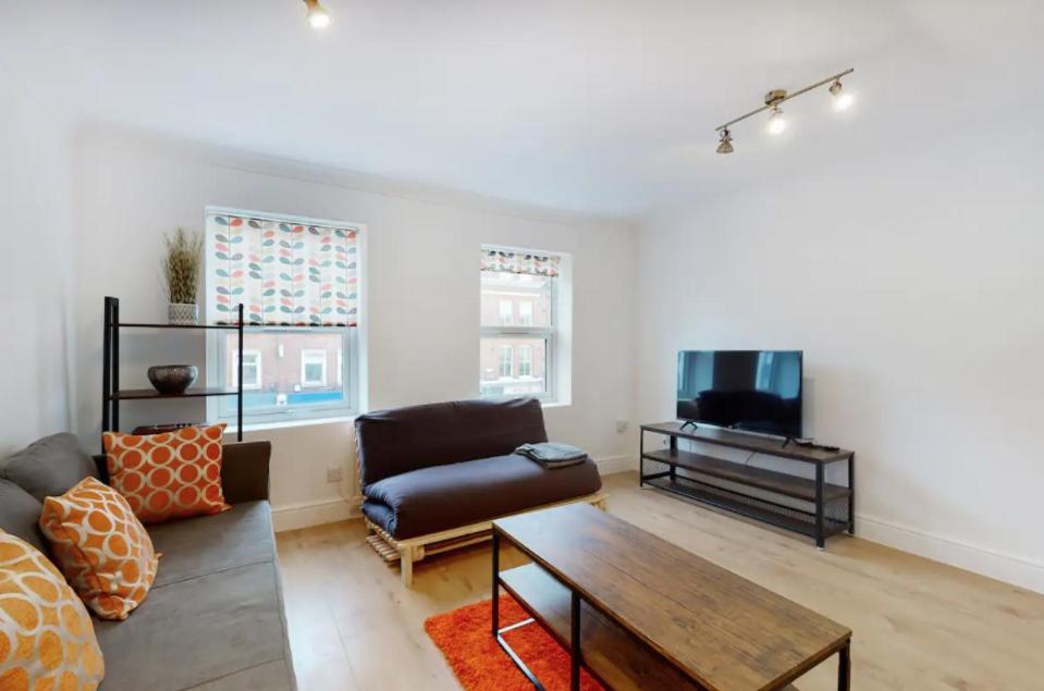 a living room with a couch and a table and a tv at Modern split level 1 bedroom flat in Aldgate in London