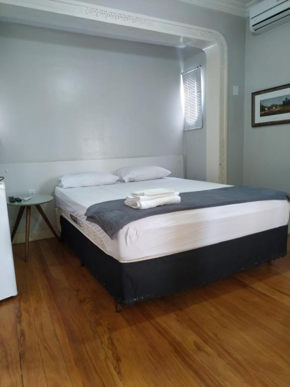 a large bed in a room with a wooden floor at Flat centro in Ubá