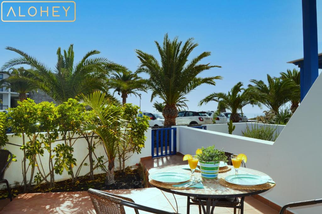 una mesa y sillas en un balcón con palmeras en Casa Maresía Las Moreras con Vista Mar en primera linea y Piscina compartida, en Playa Blanca