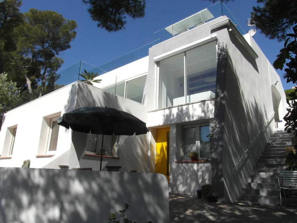 a white house with an umbrella in front of it at Estivado Sea View - Mer à 50 m et Piscine avec Spa in Cassis