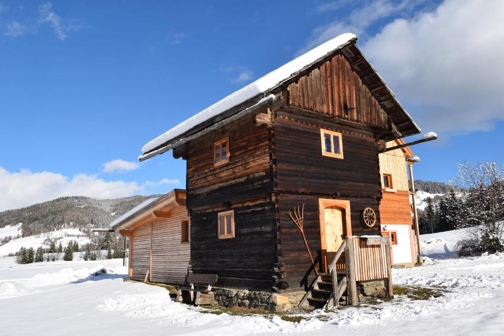 una vieja casa de madera con nieve encima en Ferienhütte Troadkostn, en Rinegg