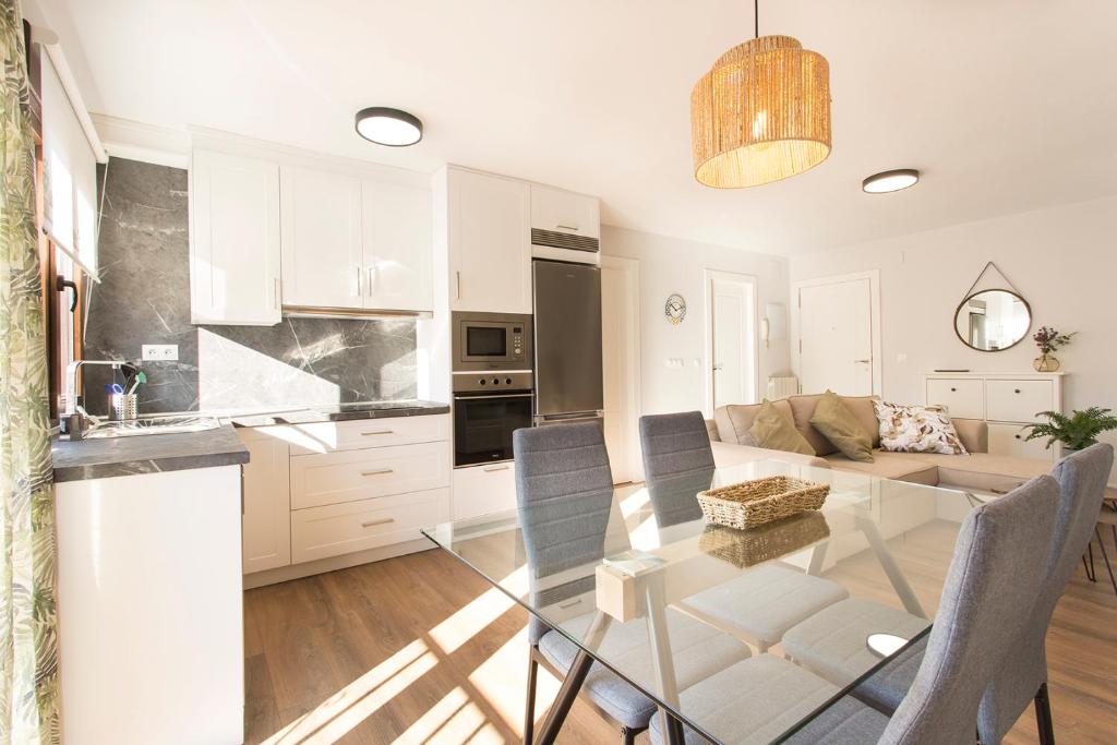 cocina y sala de estar con mesa de cristal en Apartamento Zoraida Centro, en Granada