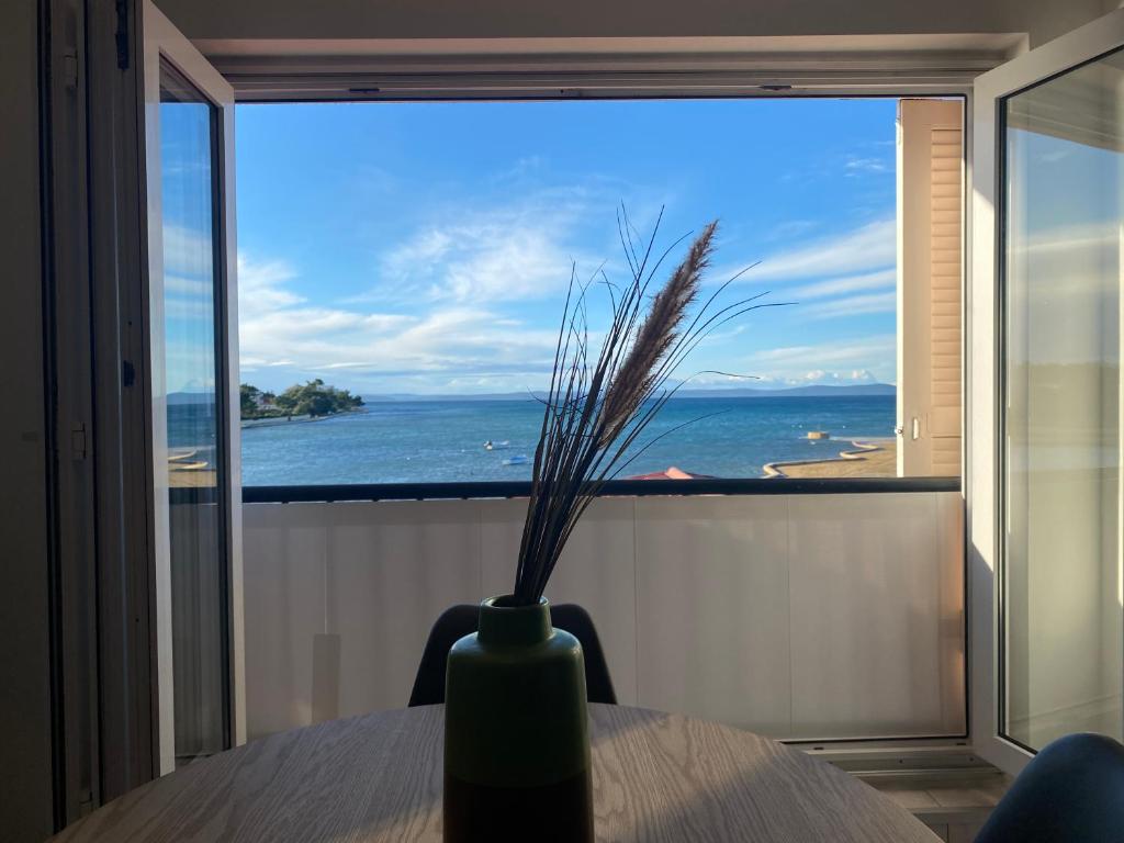 a vase on a table with a view of the ocean at Apartment Privlaka direkt am Strand mit Klima und neuem Badezimmer Haustiere sind willkommen in Privlaka