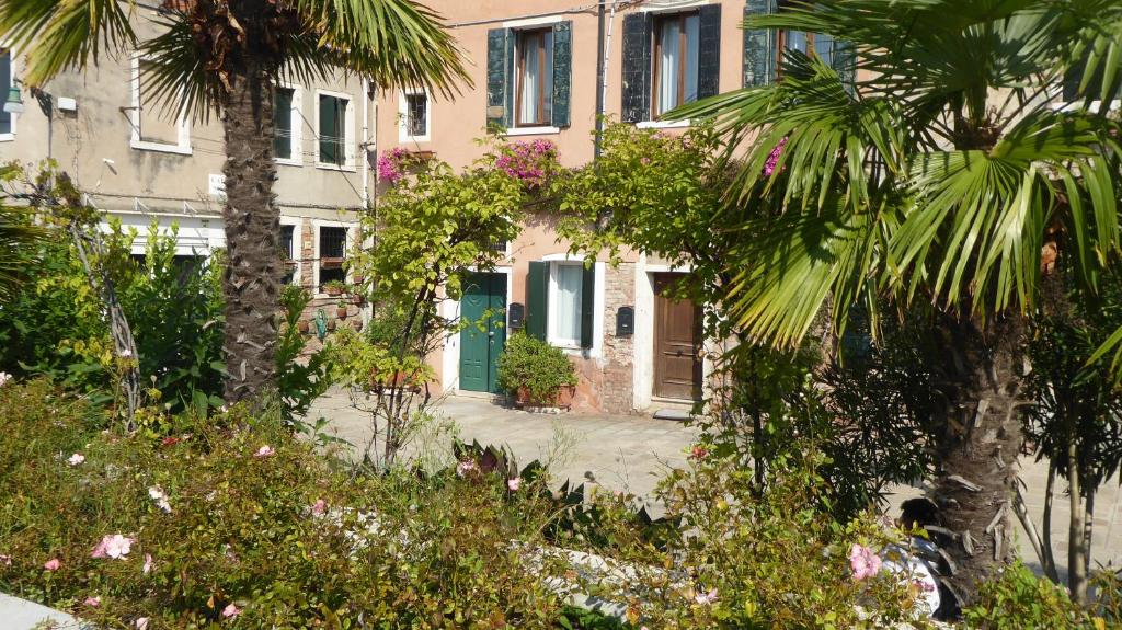 a building with a green door and some trees and flowers at Sestiere Dorsoduro, a due passi da Zattere in Venice