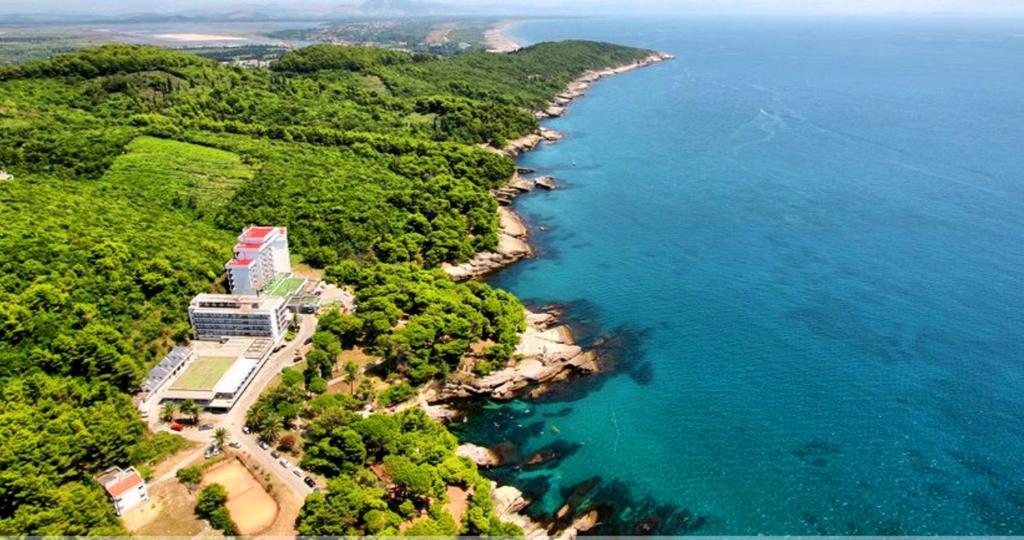 een luchtzicht op een kustlijn met een gebouw en de oceaan bij CORPUS B - Hotel Albatros in Ulcinj