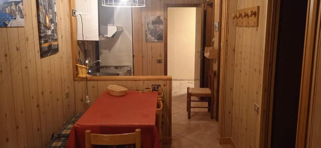 - une cuisine avec une table rouge, des chaises et un évier dans l'établissement Lago Rotondo Ski House, à Mezzana