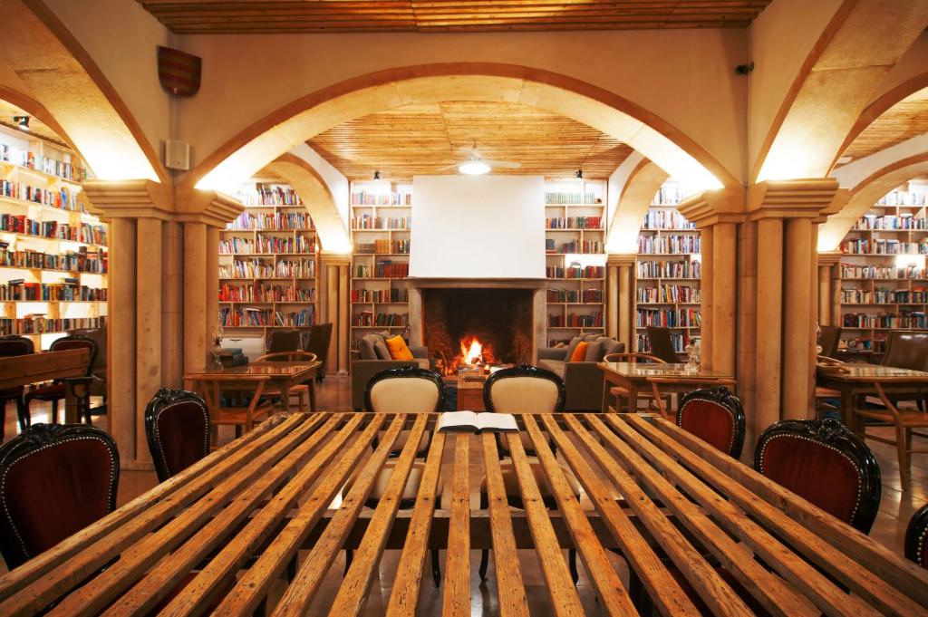 a library with a wooden table and a fireplace at The Literary Man Obidos Hotel in Óbidos