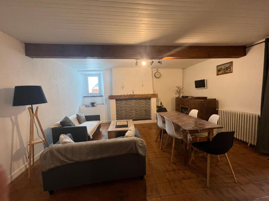 a living room with a couch and a table with chairs at Le cocon des Nestes in Arreau