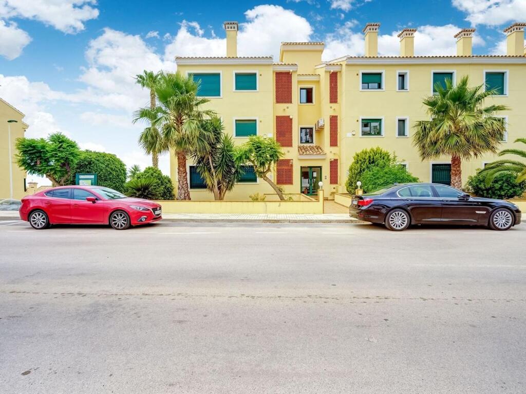 dos coches estacionados frente a un gran edificio en Belvilla by OYO Apartamento Amapola, en Villacosta