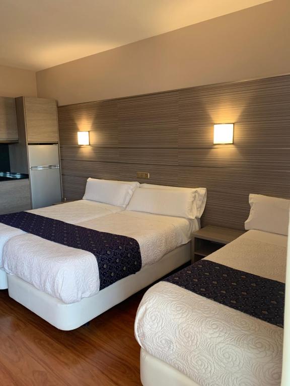 a hotel room with two beds and a refrigerator at Estudio Arriola Suite in Málaga