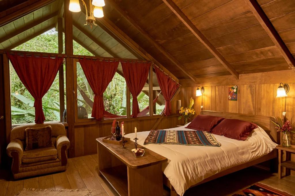 ein Schlafzimmer mit einem Bett und einem Stuhl in einem Zimmer in der Unterkunft Casa Divina Eco Lodge in Mindo