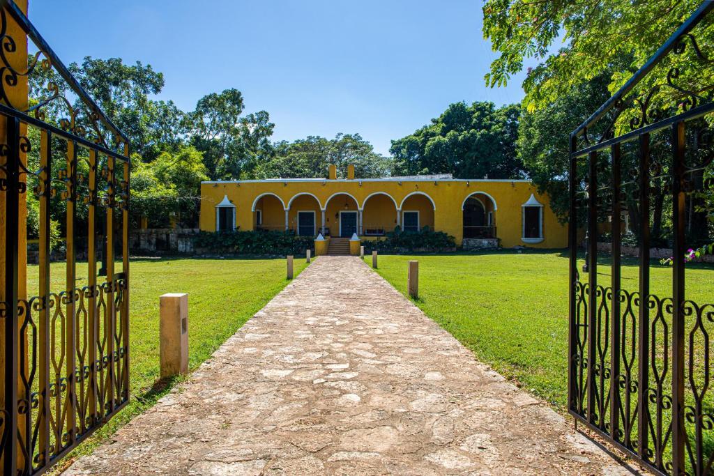 a gate leading to a yellow building in a field at Hacienda San Miguel Yucatan in Valladolid
