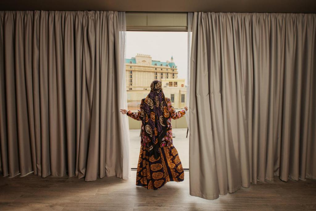 Una mujer en un hiyab mirando por una ventana en Art Club en Baku
