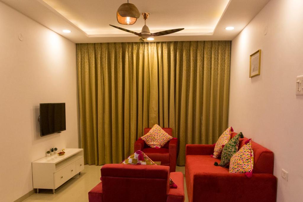 uma sala de estar com duas cadeiras vermelhas e uma cortina verde em ComfyCorner - Luxurious 2-BHK Apartment em Arpora