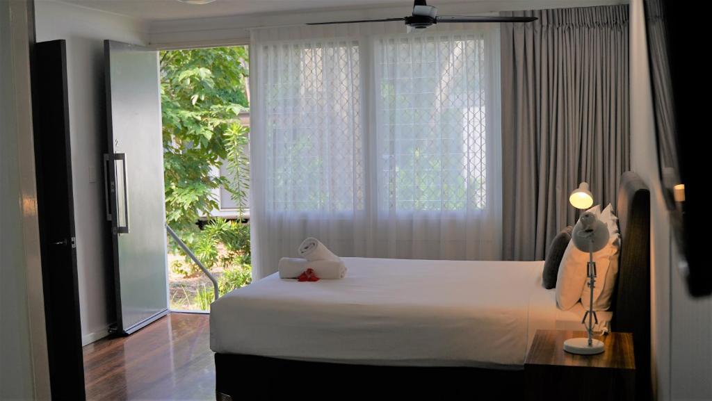 a bedroom with a white bed and a large window at Dandaloo Gardens in Arcadia