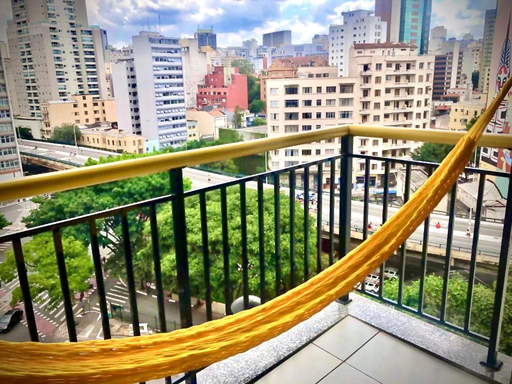 a hammock on a balcony with a view of a city at Apartamento Completo LUX com Piscina na Cobertura, República in Sao Paulo