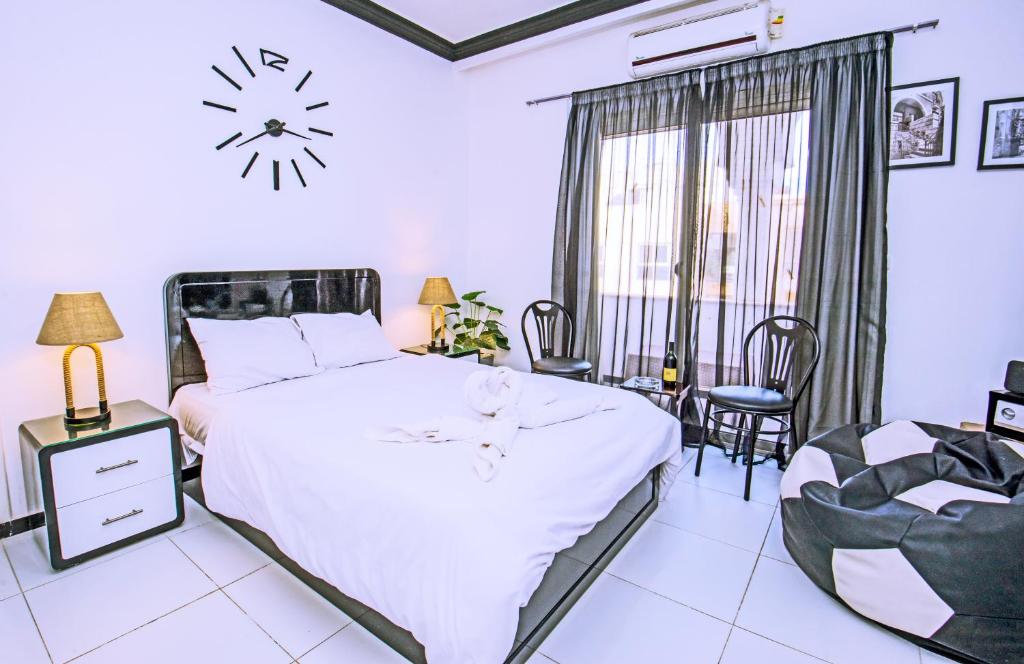 a bedroom with a large bed and a clock on the wall at Rare New Marina Hotspot With Fast Free WIFI, Balcony & Pool - Western Standards - Sheraton Plaza 414 in Hurghada