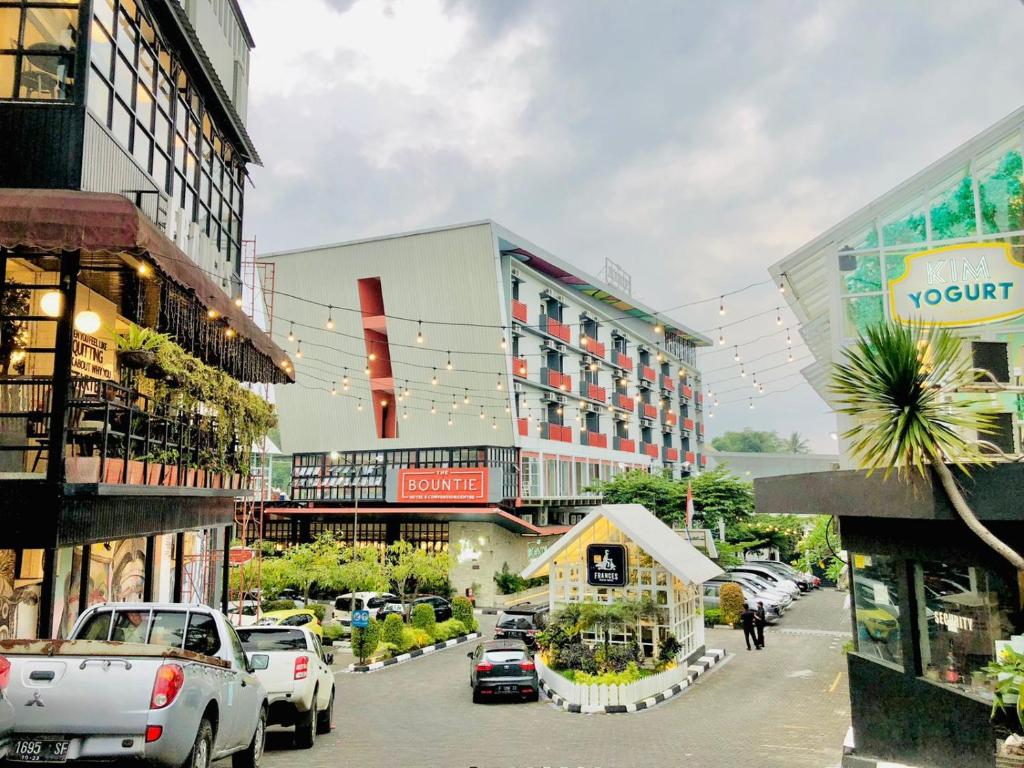una calle de la ciudad con coches estacionados frente a los edificios en The Bountie Hotel and Convention Centre Sukabumi, en Sukabumi