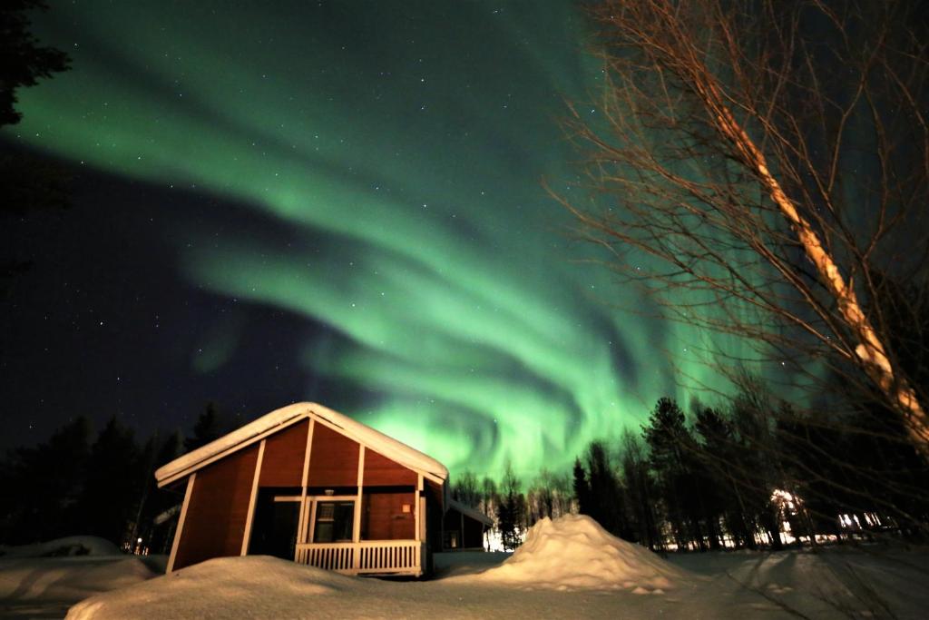 an aurora over a cabin in the snow at Seita Mökki, Äkäslompolo in Äkäslompolo