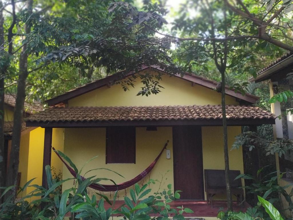a small yellow house with a brown roof at Aruá Observação de aves e natureza in Praia do Forte