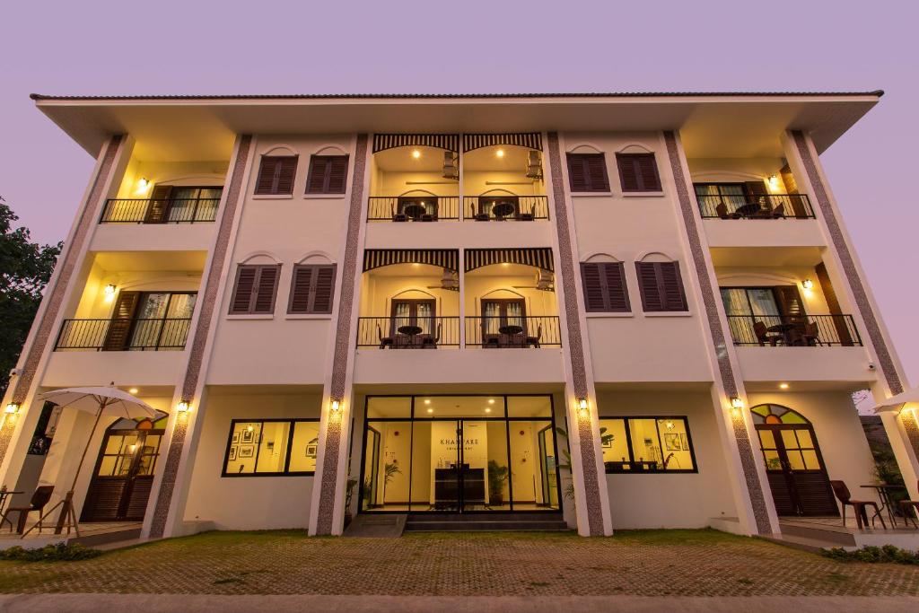 a white building with a lit up facade at night at Khampare Chiang Mai Hotel in Chiang Mai