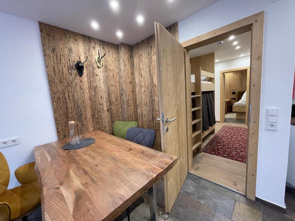 a dining room with a wooden table and a bedroom at Quality Hosts Arlberg - ALPtyrol Appartements in Sankt Anton am Arlberg