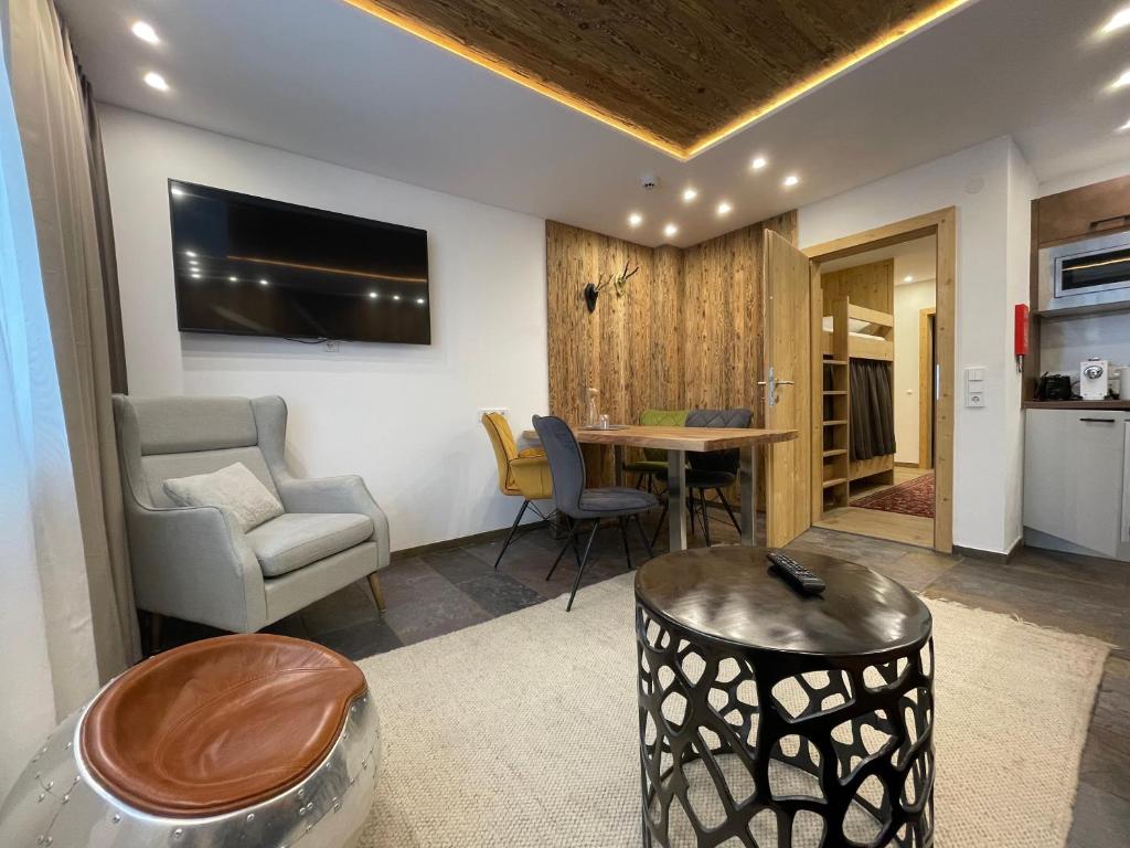 a living room with a table and a chair at Quality Hosts Arlberg - ALPtyrol Appartements in Sankt Anton am Arlberg