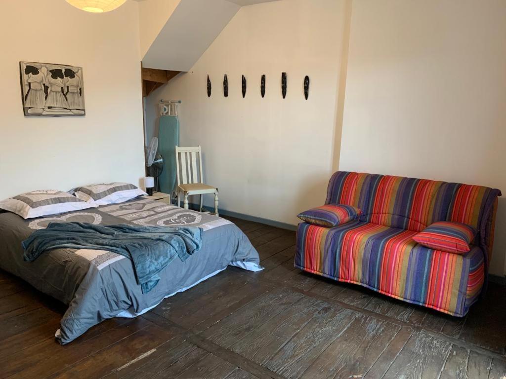 a bedroom with a bed and a couch at SUPERBE TRIPLEX MEUBLÉ TOUT CONFORT HYPER CENTRE ST CÉRÉ 3 CHAMBRES WIFI 120 M2 8 pers max in Saint-Céré