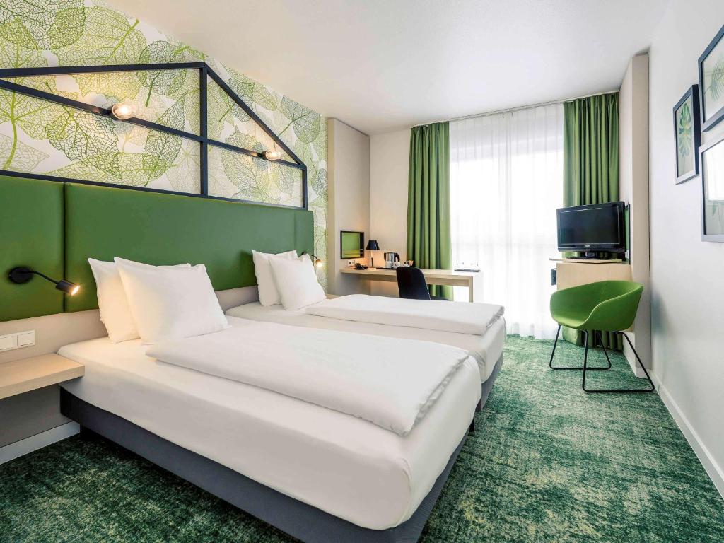 een hotelkamer met 2 bedden en een groene muur bij Mercure Hotel Hannover Mitte in Hannover