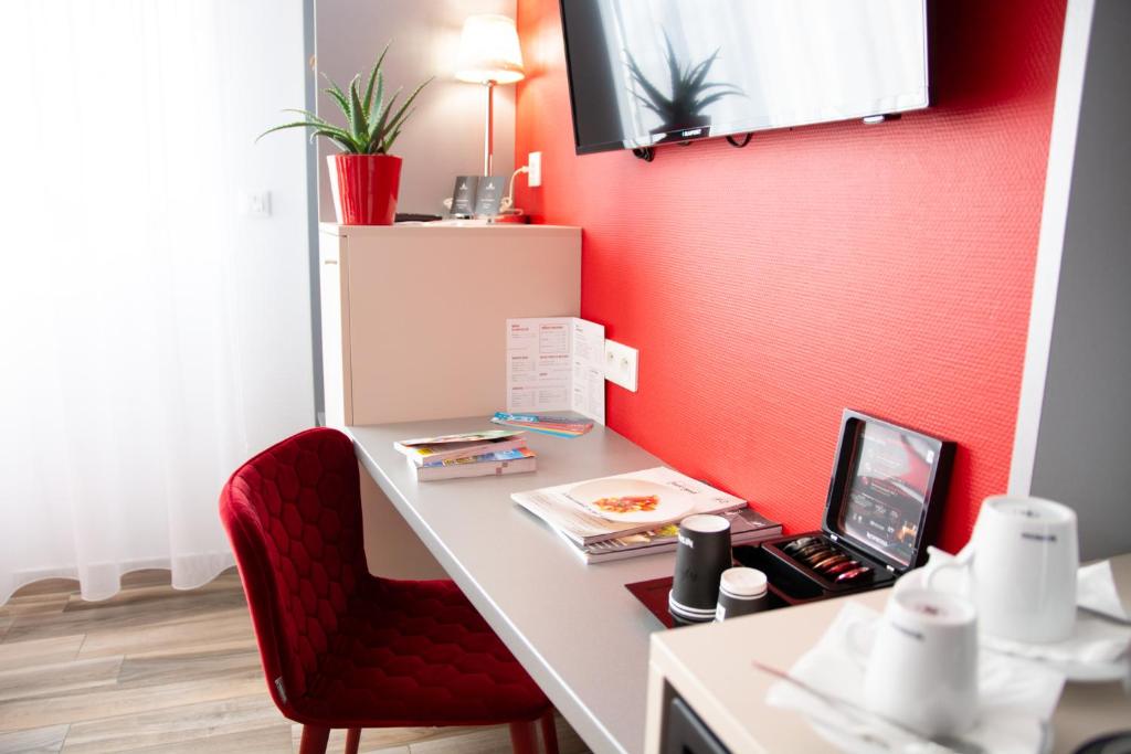 Elle comprend un bureau avec un ordinateur portable et un mur rouge. dans l&#39;établissement Colmar Hotel, à Colmar