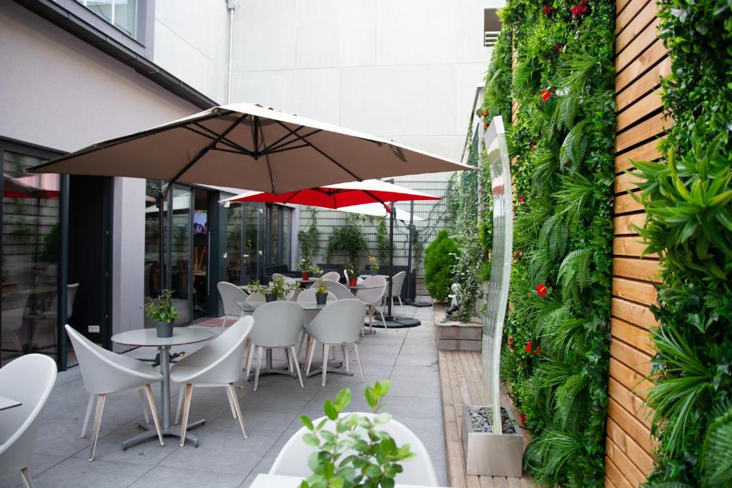 a patio with tables and chairs and an umbrella at Colmar Hotel in Colmar