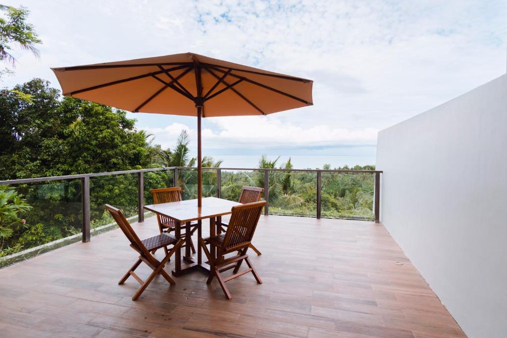 uma mesa e cadeiras com um guarda-sol num deque em Melase Hill Villa em Lajor