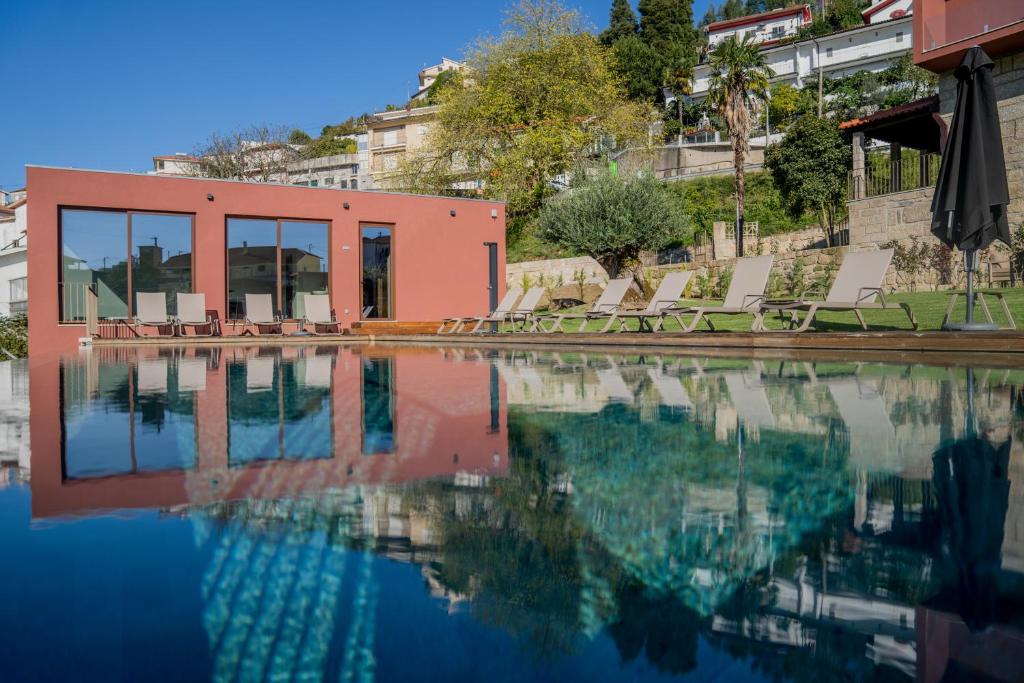 une piscine d'eau avec des chaises et un bâtiment dans l'établissement Quinta de Santo António - Country House & Villas, à Marco de Canavezes