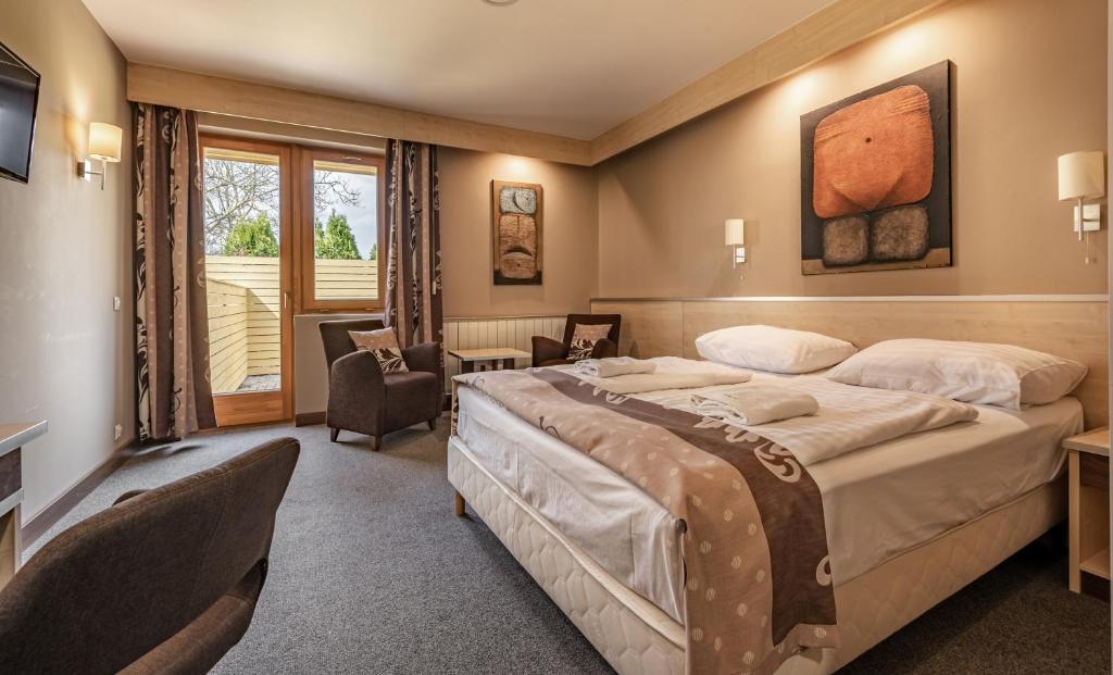 a hotel room with a large bed and a television at Hotel Vineyard Inn - Szőlőskert in Nagykanizsa