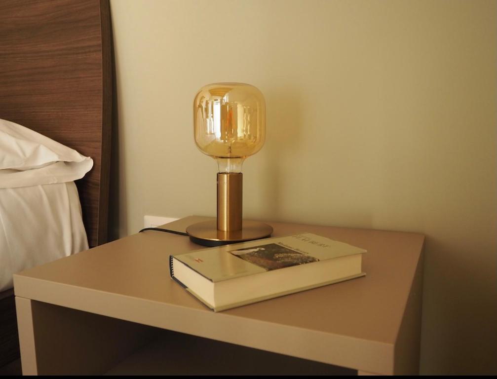 una mesa con una lámpara y un libro sobre ella en I Giardini Di Zelda, en Policoro