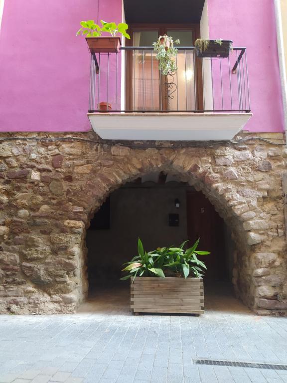 ein rosafarbenes Gebäude mit einem Balkon und Pflanzen darauf in der Unterkunft Casa Díaz in El Pont de Suert